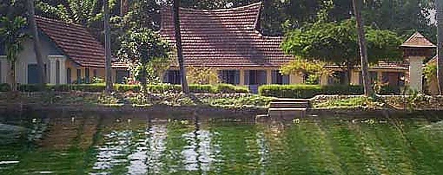 The house seen across the backwater, its tiled roofs reflected in the water